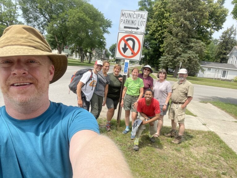 The group posing by a blaze in the Trail Town of Kalkaska after a second blazing hot day.